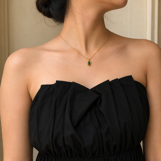 Woman wearing 18k gold-plated hexagon pendant necklace with green zircon stone, paired with a black strapless dress - Miromor
